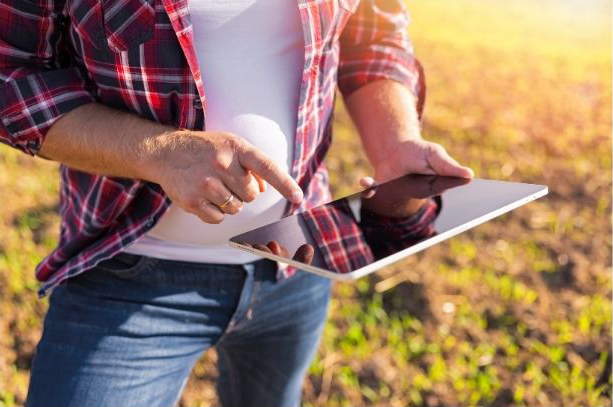 Farmer recording data on an electronic tablet in a field
